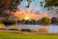 Empty park bench sits by the water with the light of sunset in the background Royalty Free Stock Photo