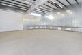 Empty parking garage, warehouse interior with large white gates and windows inside