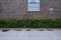 Empty parking near red brick wall and green bushes, deadpan photodraphy