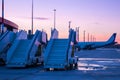 Empty passenger boarding steps near the aircraft on the airport apron against the backdrop of a picturesque crimson sunset