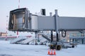 Empty passenger boarding bridge and air-stairs at winter airport apron Royalty Free Stock Photo