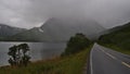 Empty paved country road 85 at Gullesfjord, HinnÃÂ¸ya, VesterÃÂ¥len in Norway on rainy day with vegetation, fjord and mountains. Royalty Free Stock Photo