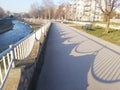 Empty paved river embankment with shadow from fence.