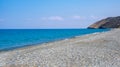 Empty pebble beach with blue calm water against blue sky