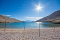 Empty pebble beach with wooden sticks and glittering sea in the bay