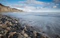 Empty pebble tropical beach under cliffs with windwaves and cloudy sky