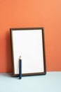 Empty photo frame with colored pencil on gray shelf. red wall background Royalty Free Stock Photo