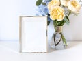 Empty photo frame with a flower bouquet in a vase on the white background. Royalty Free Stock Photo