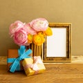 Empty photo frame with gift boxes and flowers on wooden table Royalty Free Stock Photo