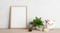 Empty photo frame mockup on wooden table with cow doll plant pine cone and gift box. Art and decoration concept. 3D illustration Royalty Free Stock Photo