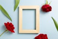 Empty photo frame with red rose flowers on blue background Royalty Free Stock Photo