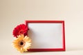 Empty photo frame with red and yellow gerbera daisy flowers on pastel beige background. Picture frame mockup with flowers, copy Royalty Free Stock Photo