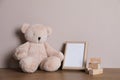 Empty photo frame, teddy bear and building blocks on wooden table near grey wall. Space for design Royalty Free Stock Photo