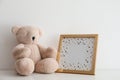 Empty photo frame and teddy bear on table near white wall. Space for design Royalty Free Stock Photo