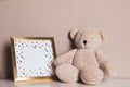 Empty photo frame and teddy bear on white table near grey wall. Space for design Royalty Free Stock Photo