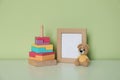 Empty photo frame, toy bear and pyramid on white table near light green wall. Space for design Royalty Free Stock Photo