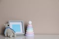 Empty photo frame, toy bear and ring pyramid on white table near grey wall. Space for design Royalty Free Stock Photo