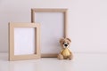 Empty photo frames and toy bear on table near white wall. Space for design Royalty Free Stock Photo