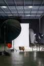 Empty photo studio with modern interior and lighting equipment. Preparation for studio shooting: empty chair and studio lighting.