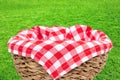 Empty picnic basket. Close-up of a empty straw basket therein a red checkered napkin isolated on a green grass background. For Royalty Free Stock Photo