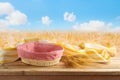Empty picnic basket and tablecloth on wooden table over wheat field landscape background. Shavuot holiday mock up for design and Royalty Free Stock Photo