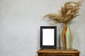 empty picture frame mockup and golden reeds plant vase on wooden table near grunge wall, autumn fall concept, Royalty Free Stock Photo