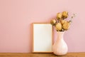 Empty picture frame with vase of dry rose flowers on wooden table Royalty Free Stock Photo