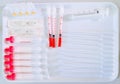 Empty pipettes, droppers, vails and syringe on white tray on laboratory worktop