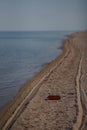 Empty plastic bottle lying on the beach. Environmental pollution. Tire tracks on the sand. Summer seascape Royalty Free Stock Photo