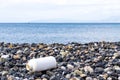 Empty plastic bottle on a pebble beach, the concept of plastic pollution. Royalty Free Stock Photo