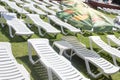 Empty plastic deck chairs on a grassy beach