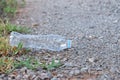 An empty of plastic drinking bottle littering on the pathway floor with blur green grass and small rocks background Royalty Free Stock Photo