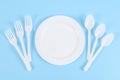 Empty plastic plate with forks and spoons on the sides on a blue. Royalty Free Stock Photo