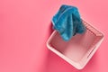 Empty plastic square basket for washing with blue soft towel lies on pink countertop in laundry Royalty Free Stock Photo