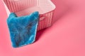 Empty plastic square basket for washing with blue soft towel lies on pink countertop in laundry Royalty Free Stock Photo