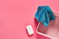 Empty plastic square basket for washing with blue soft towel near antibacterial soap lies on pink countertop in laundry Royalty Free Stock Photo