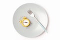 Empty plate with alarm clock and fork on white background, intermittent fasting concept. Royalty Free Stock Photo