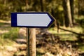 Empty plate on the background of a green forest wall. A signpost mounted on a wooden stake in the forest. Royalty Free Stock Photo