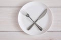 Empty plate with crossed fork and knife on white wood top view Royalty Free Stock Photo