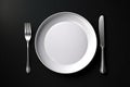 Empty plate with fork and knife on black. Served cutlery, minimal dark table setting. Menu mockup, space for text, diet concept.