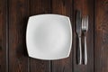 Empty plate, fork and knife on the dark wood background Royalty Free Stock Photo
