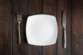 Empty plate, fork and knife on dark wood background Royalty Free Stock Photo