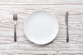 Empty plate fork knife silverware white wooden table background Royalty Free Stock Photo