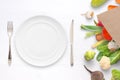 Empty plate, fork and knige on table with vegetables in paper bag beside Royalty Free Stock Photo