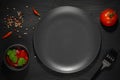 Empty plate, fork, tomato, ketchup and spices on black background top view Royalty Free Stock Photo