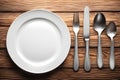 Empty plate, knife, fork and spoon on wooden table. Top view Royalty Free Stock Photo