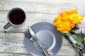 a plate with a knife and fork and tea with a bouquet of yellow roses on a white wooden background Royalty Free Stock Photo