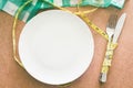 Empty plate with measure tape,knife and fork on wooden table Royalty Free Stock Photo