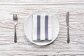 Empty plate napkin fork knife silverware white wooden table background Royalty Free Stock Photo