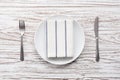 Empty plate napkin fork knife silverware white wooden table background Royalty Free Stock Photo